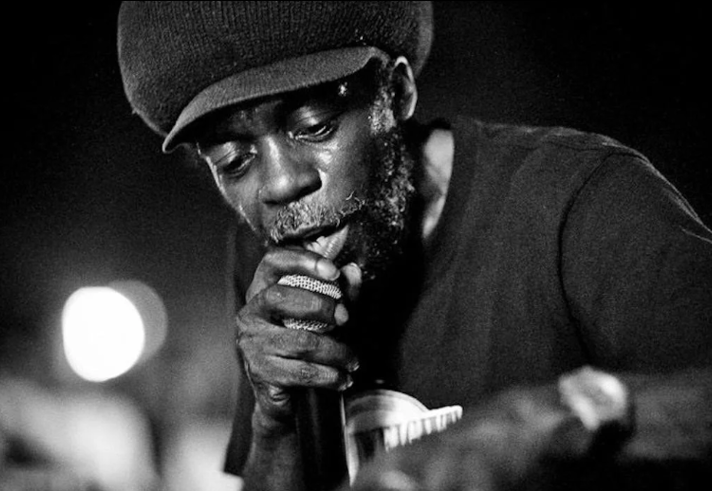 A black and white shot of a man singing into a microphone.