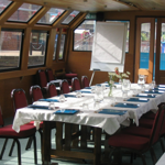 Inside the A&G Passenger Boat, with a long table set up for a meal.