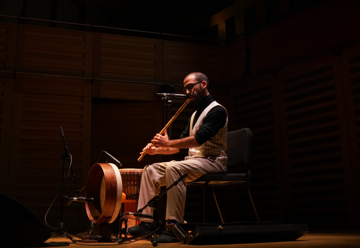 Faris Ishaq performing live on stage under atmospheric lighting.