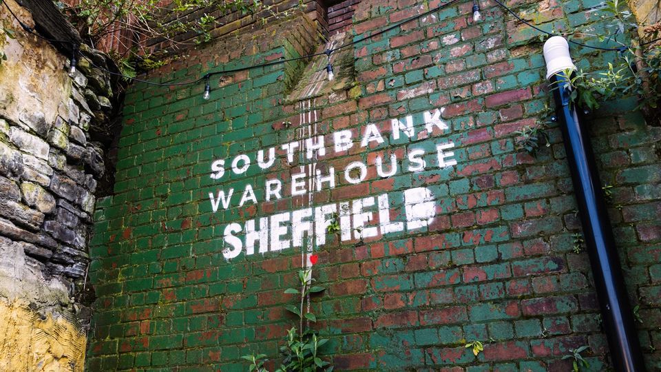 Southbank Warehouse stencilled on to a red brick wall that is partially covered in peeling green paint.