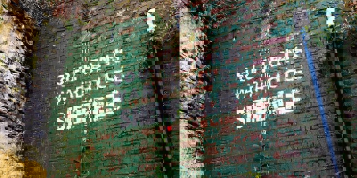 Southbank Warehouse stencilled on to a red brick wall that is partially covered in peeling green paint.