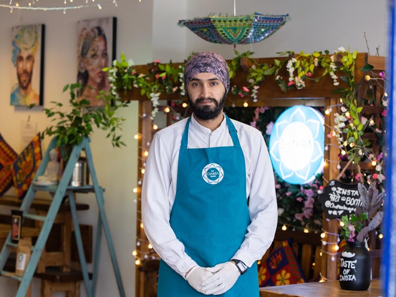 Inside The Chakra Lounge stands a member of staff wearing a blue apron.