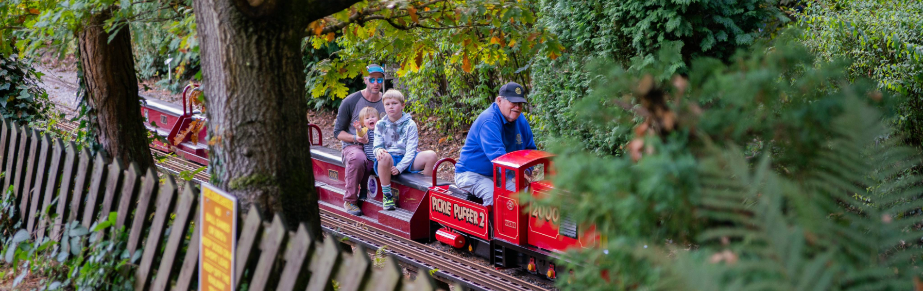 A family rides on a miniature steam train through a wooded area at the Abbeydale Miniature Railway in Sheffield.
