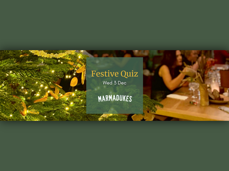 Close-up of a decorated Christmas tree with warm white lights and dried orange slices, next to a green square sign that reads “Festive Quiz, Wed 3 Dec, Marmadukes.” In the background, a wooden table is set with glassware, a gold vase, and festive decorations in a cozy indoor setting.