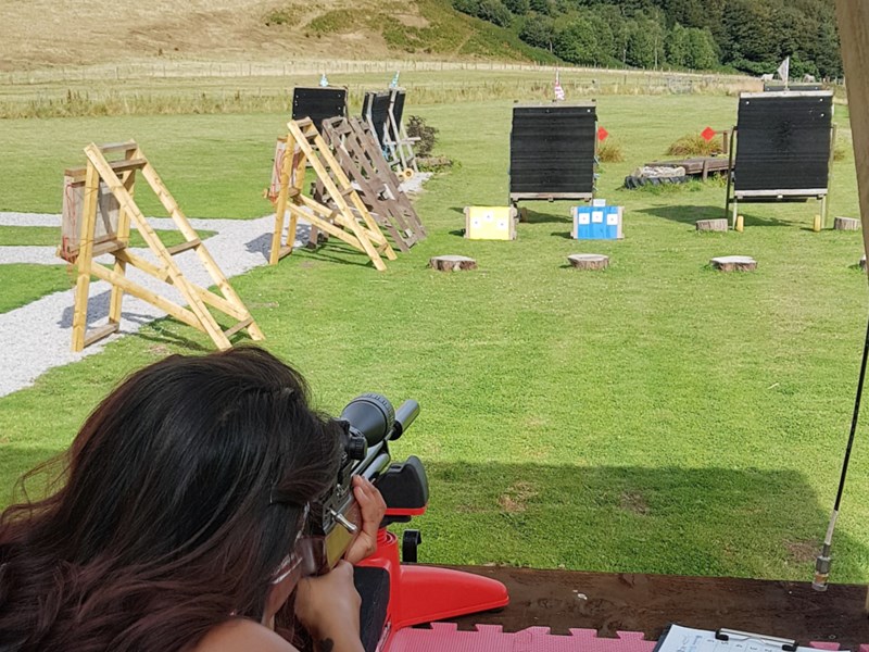 A person aiming a rifle at a target on a shooting range.