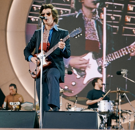 Alex Turner singing and playing guitar on stage at the Arctic Monkeys show in Hillsborough Park