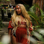 A woman stands in a room that is filled with all sorts of exotic plants.