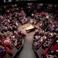 The Crucible Theatre is filled with people waiting for a concert to start. In the centre of the stage is a grand piano.