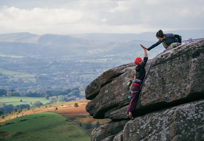 Two climbers on a rocky outcrop high-fiving each other.