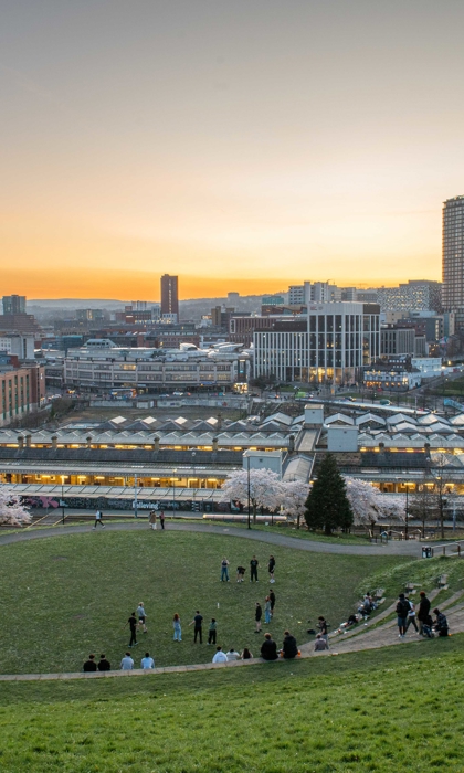 A striking cityscape view of Sheffield at dusk taken from South Street Park amphitheatre during springtime with blossom on the trees