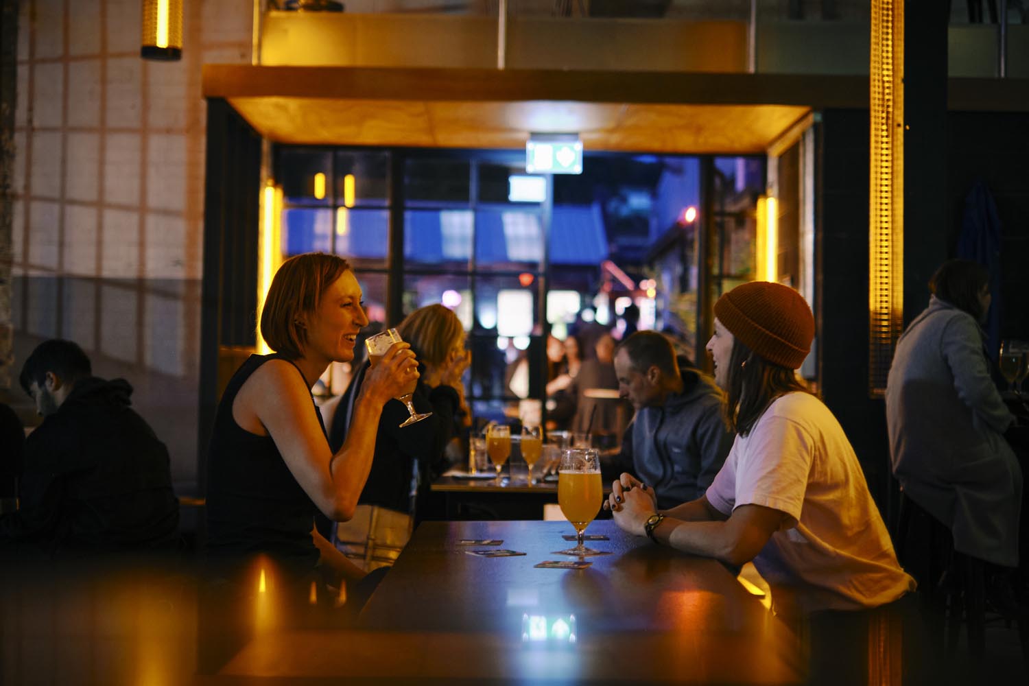 Two people drinking across the table from one another in Factory Floor 