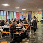 A communal area with tables and benches, full of people.