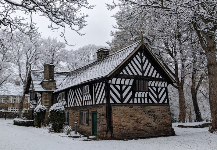 The Bishop's House in the snow. The bottom half of the building is stone and the top half is black and white timbers.
