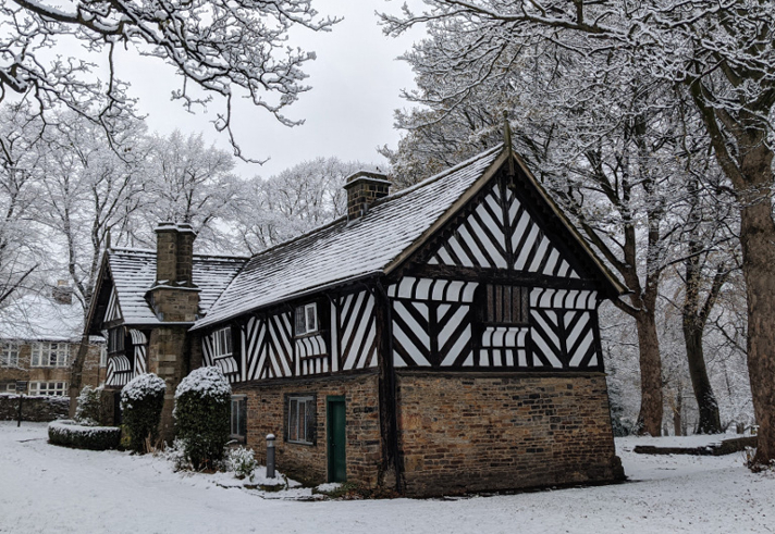 The Bishop's House in the snow. The bottom half of the building is stone and the top half is black and white timbers.