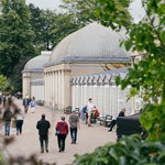 People are strolling along the wide path that runs along the length of the glass house in Sheffield Botanical Gardens.