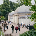 People are strolling along the wide path that runs along the length of the glass house in Sheffield Botanical Gardens.