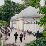 People are strolling along the wide path that runs along the length of the glass house in Sheffield Botanical Gardens.