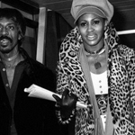 A black and white image of two people walking through a public space.