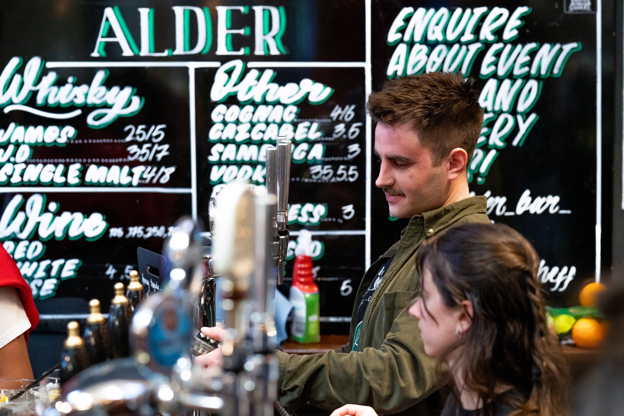 Two people working behind the bar at Alder.