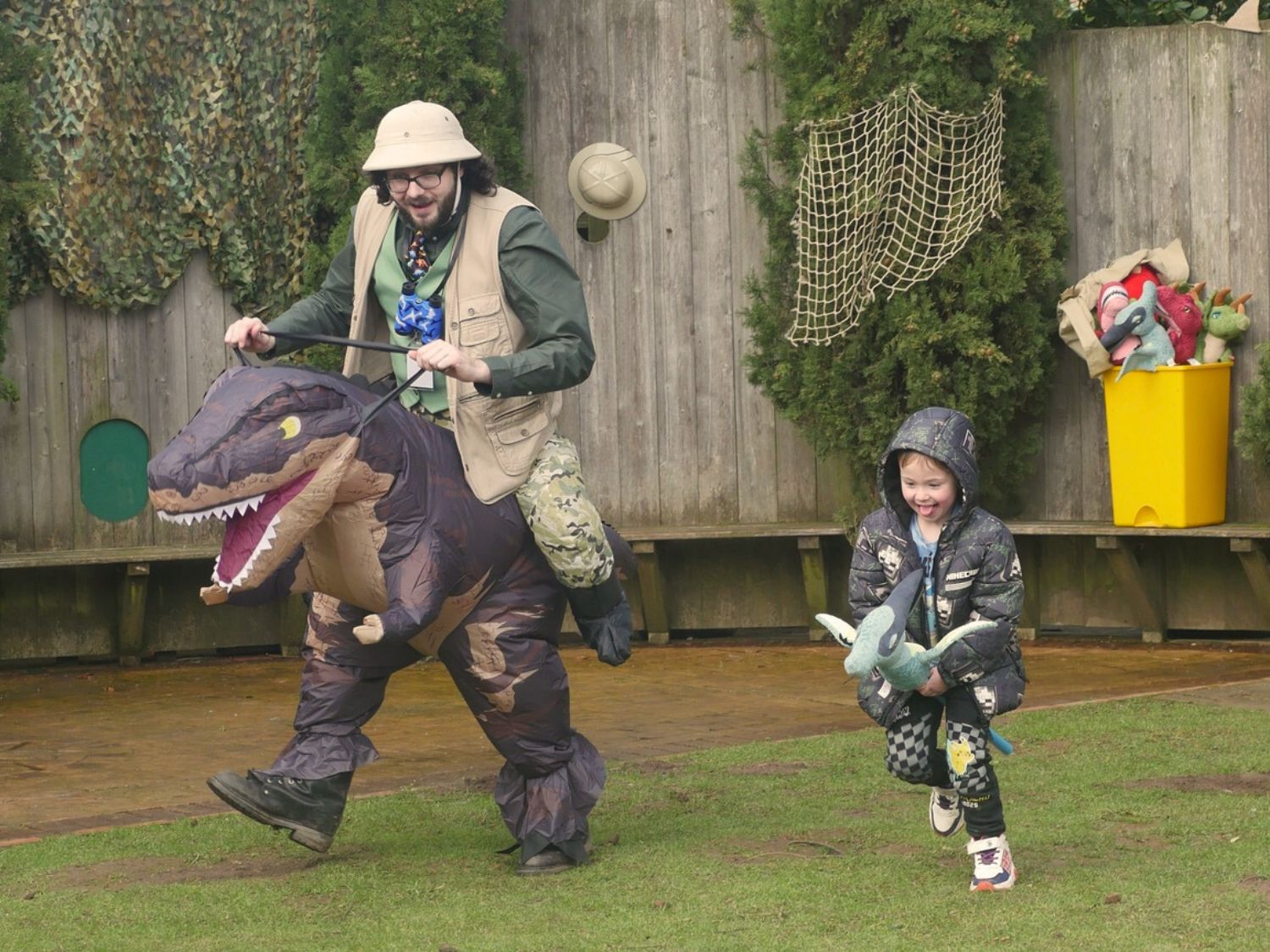 An adult and a child pretending to ride around on dinosaurs.