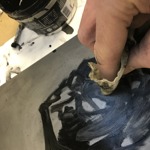 A close up of a person rubbing a printing plate with a small rag.