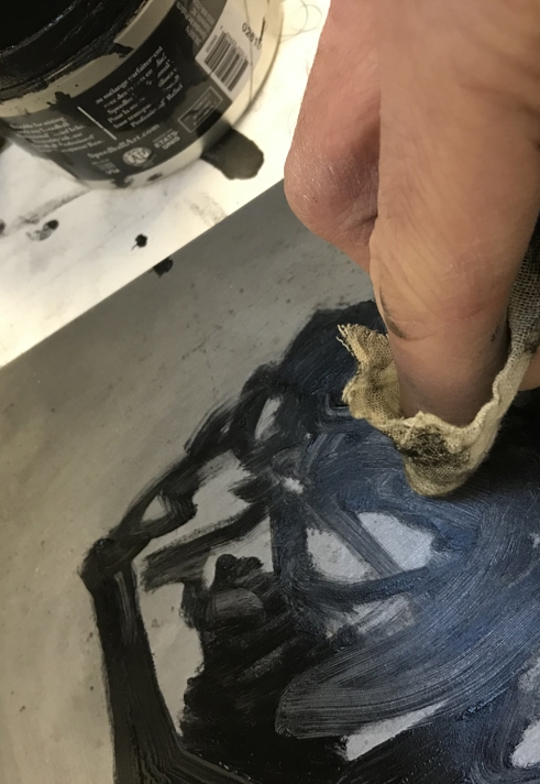 A close up of a person rubbing a printing plate with a small rag.
