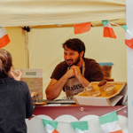 A food vendor serving pastries at a stall decorated with Italian flags.