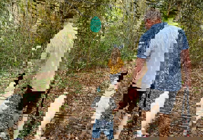 A family, in the woods, on an Easter Egg Hunt.