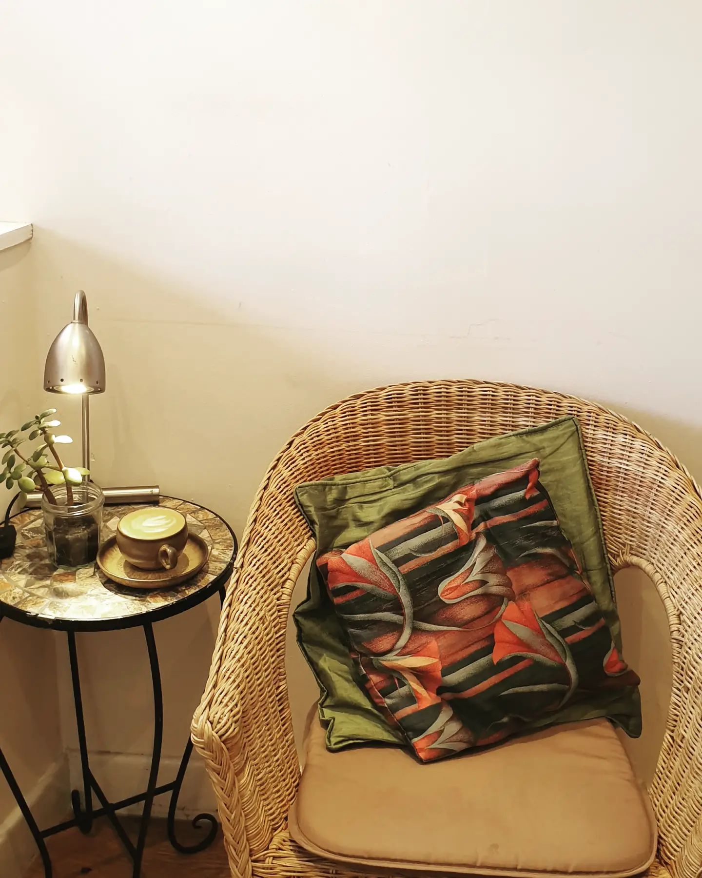 A wicker chair, with a coffee on a small side table, at the Dana Cafe.