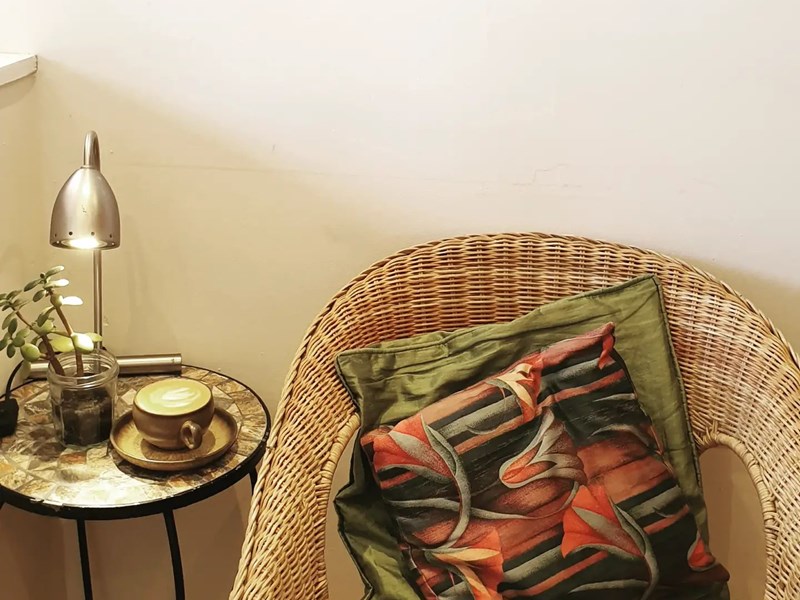 A wicker chair, with a coffee on a small side table, at the Dana Cafe.