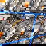Rows of metal beer casks stored on blue metal shelving inside a warehouse. Each cask has an identification label attached.