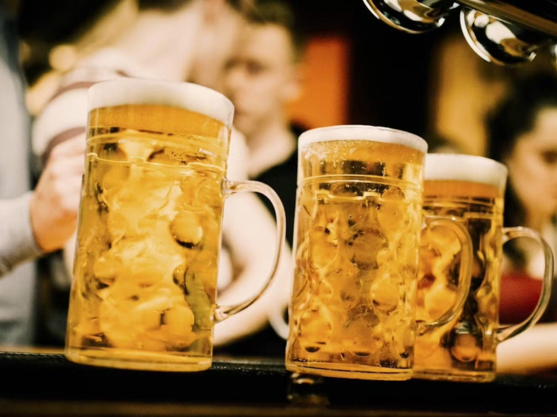 Three steins of beer on a bar top.