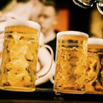 Three steins of beer on a bar top.