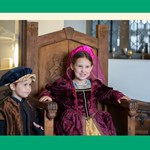 A girl and a boy dressed in Tudor costumes, having fun.