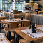 Inside Forbici, with tables and chairs throughout the restaurant and a wood fired pizza oven in the corner.