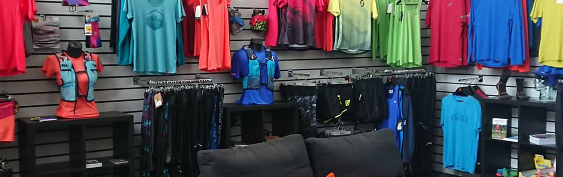 The interior of a shop, with lots of sporting clothes, shoes and equipment on display.