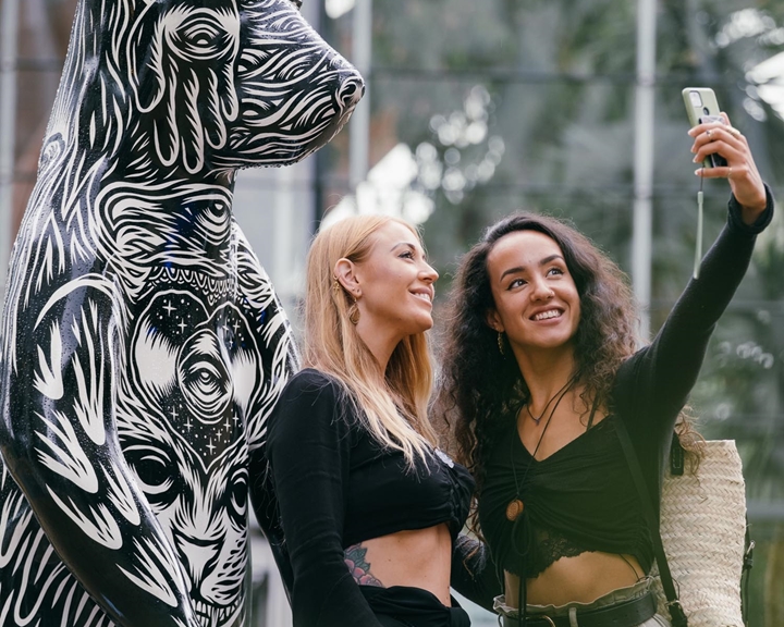 Two women taking a selfie in front of a statue of a bear that has been decorated by Sheffield artist Tom J Newell. The bear is one of The Bears of Sheffield which was a large public sculpture trail that span the city of Sheffield throughout the summer of 2021.