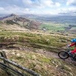 Two people mountain biking along a muddy track out in the countryside.
