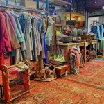 Inside The Warehouse with shelves and tables covered in things to buy and rails full of clothes.