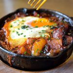 A close up of an iron skillet cooking food on a stove.
