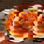 A plated pub meal consisting of a golden pie served with thick-cut roasted potatoes, gravy, and a small bowl of mushy peas.