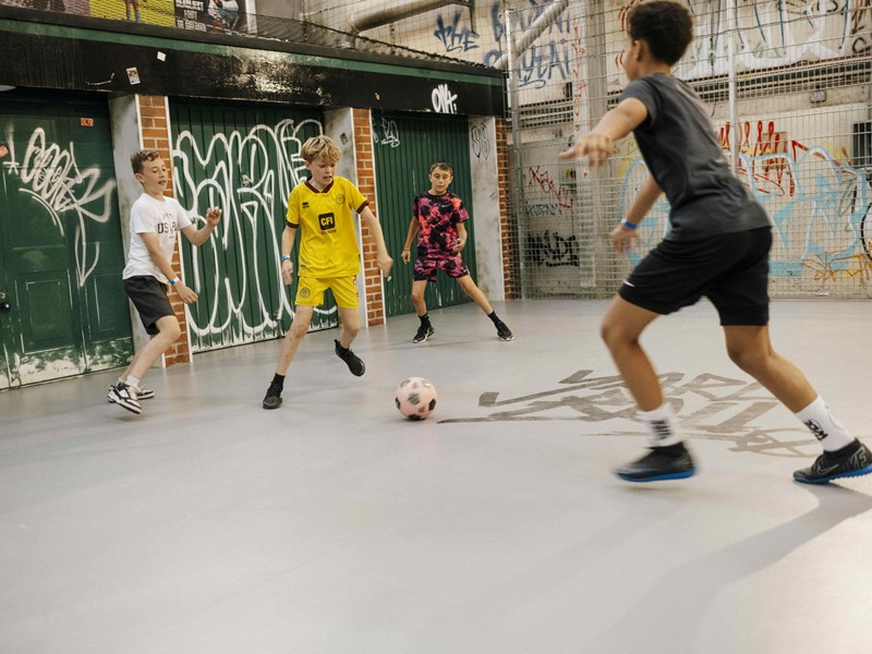 Four boys play indoor football at Yard Ball.