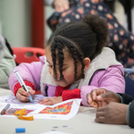 Adults and children sat round a table having fun with arts and crafts.