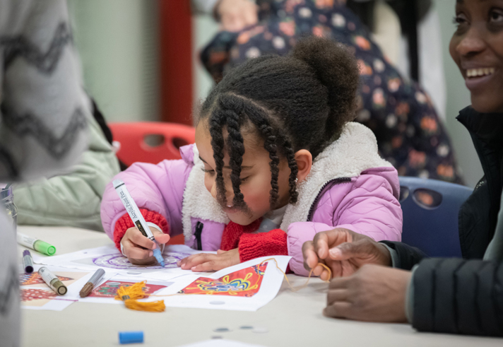 Adults and children sat round a table having fun with arts and crafts.