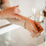 A close-up of a person holding a piece of jewellery for another person to have a look at.