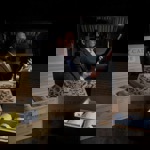 Person holding a wine bottle in a dimly lit setting, surrounded by open wooden crates containing wrapped bottles. 