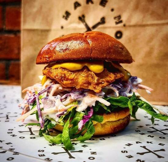 A tall burger filled with veggies, toppings and sauces.