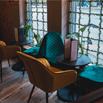 Beautifully upholstered chairs with tables by the window at Boulevardier