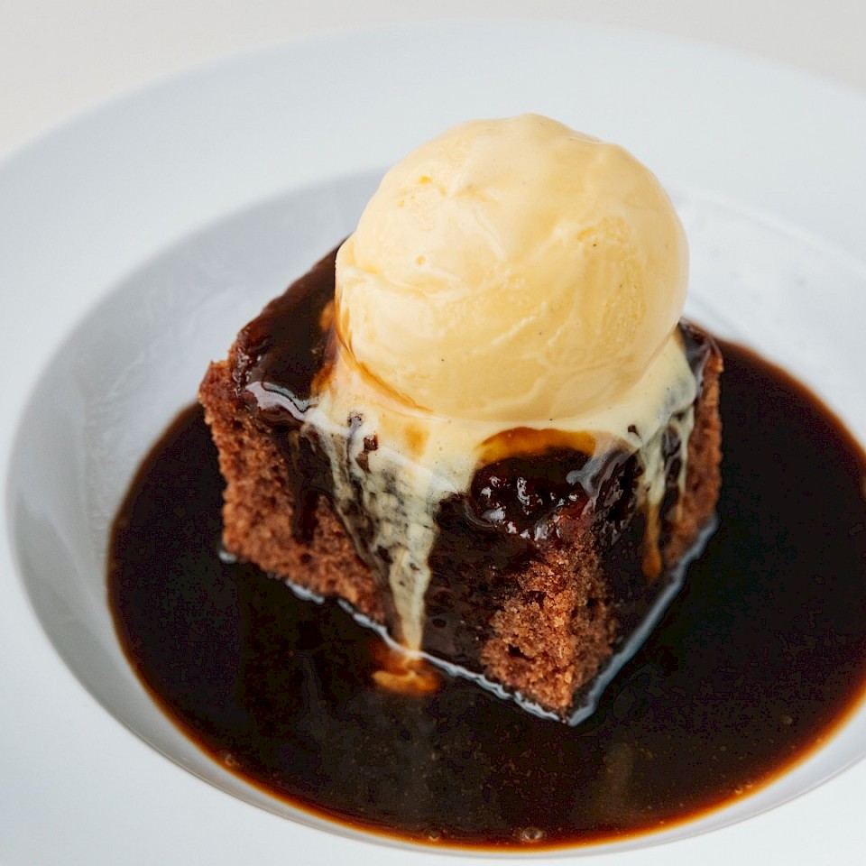 A cake covered in sauce with a scoop of ice cream on top.