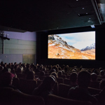 Cinema room full of people, with a cinema screen showing a snowy mountain